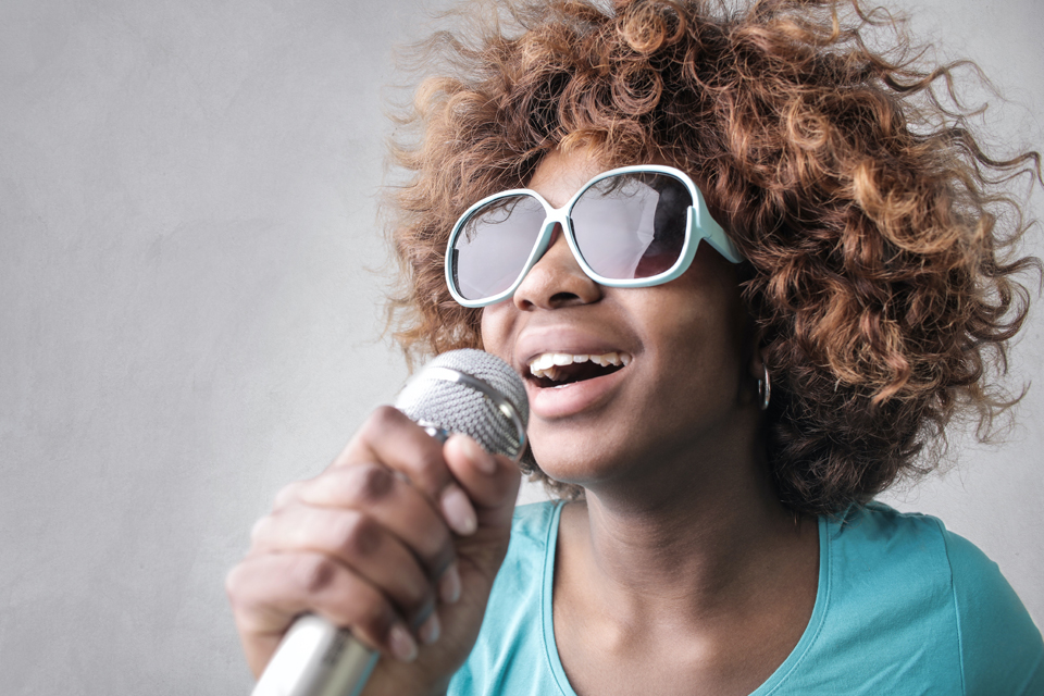 African American female wearing sunglasses and holding a microphone